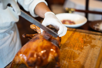 The chef is cutting the duck skin from the Beijing duck with a very sharp knife at a famous Chinese restaurant.