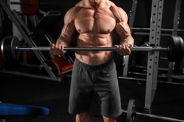 Fototapeta na wymiar Muscular man training with barbell in gym