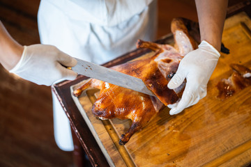 The chef is cutting the duck skin from the Beijing duck with a very sharp knife at a famous Chinese restaurant.