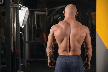 Fototapeta na wymiar Muscular man standing near mirror in gym
