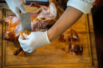 The chef is cutting the duck skin from the Beijing duck with a very sharp knife at a famous Chinese restaurant.