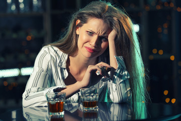 Young woman drinking alcohol and smoking cigar in bar