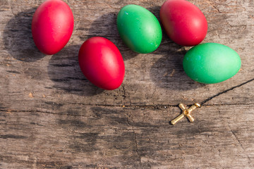 Painted Easter eggs and Christianity golden cross on rustic wooden background