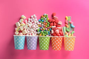 Fototapeten Paper cups with tasty candies on color background © Pixel-Shot