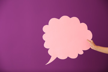 Female hand with blank speech bubble on color background