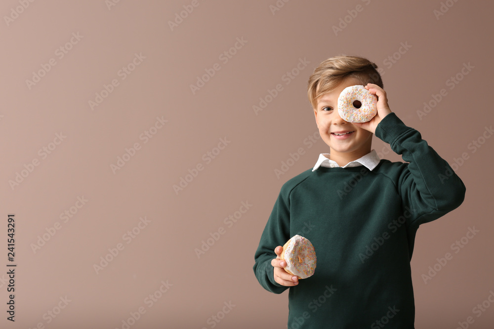 Wall mural cute little boy with donuts on color background