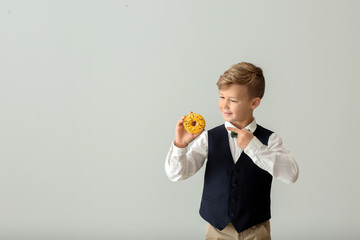Cute little boy with donut on light background