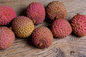 Raw pink and orange lychees on a wooden background