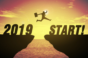 Silhouette of business man jump between cliff. keep go on to success concept at 2019 START over a...