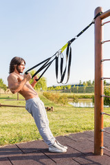 Fit young man exercising biceps curls in the park