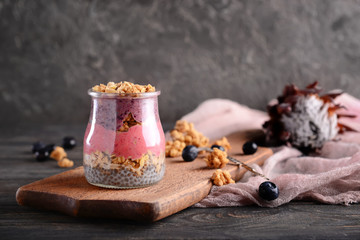 Jar with tasty granola and yogurt on wooden table