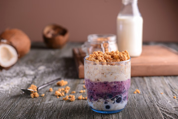 Glass with tasty granola and yogurt on wooden table