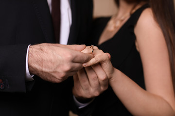 Young man putting ring on finger of his fiancee after marriage proposal, closeup