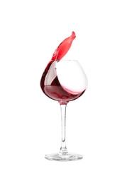 Glass with red splashing wine on white background