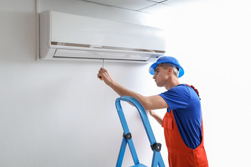 Male technician repairing air conditioner indoors