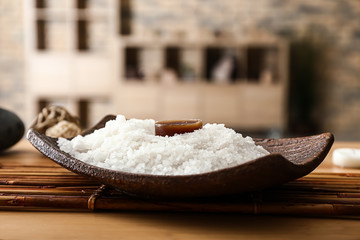 Plate with sea salt and candle on table in spa salon