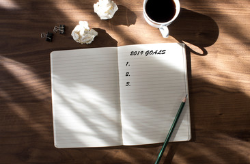 2019 goals list with notebook , cup of coffee over on wooden background.	