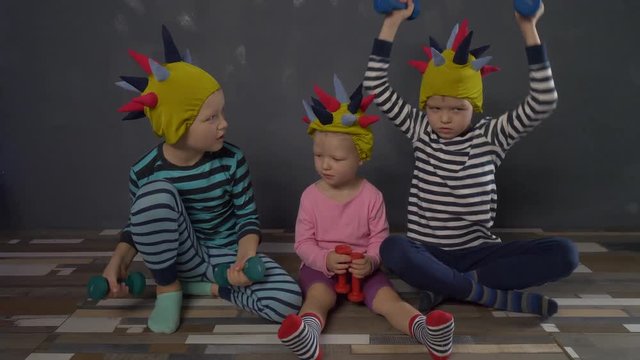 Cheerful children in carnival caps with colorful needles, like hedgehog, do gymnastics with dumbbells. Children enjoy winter vacations together. concept of traditional family holiday