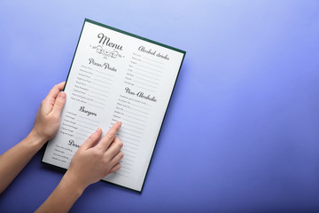 Female hands with menu on color background - obrazy, fototapety, plakaty