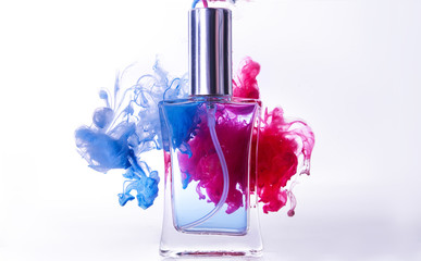 Bottle of perfume in color smoke on white background