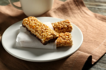 Plate with tasty granola bars on table