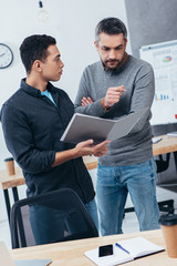 professional businessmen holding folder with papers and discussing project in office