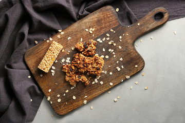 Tasty baked granola and bar on wooden board