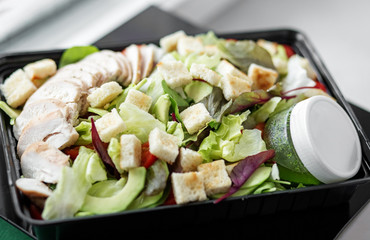 Vegetable and chicken salad and pesto sauce in lunch box. The concept of food and food delivery.