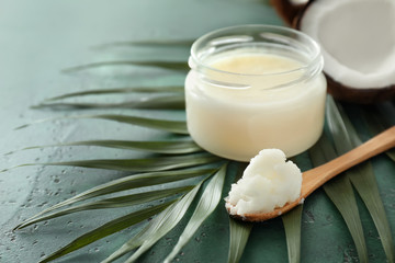Jar and spoon with coconut oil on color background