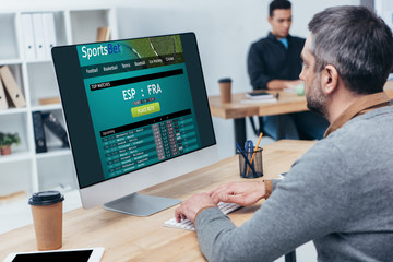 Fototapeta na wymiar businessman using desktop computer with sports bet website on screen in office