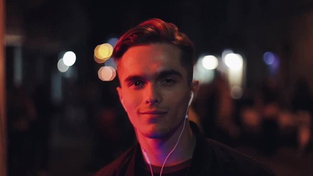 Attractive man with headphones at night on the streets close up portrait
