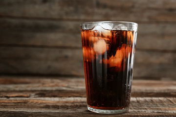 Glass of soda with ice on wooden table