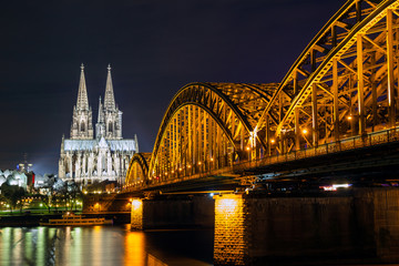 Fototapeta premium Riverside view of the Cologne Cathedral and railway bridge over the Rhine river, Germany