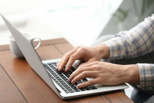 Young man working with laptop at home, closeup