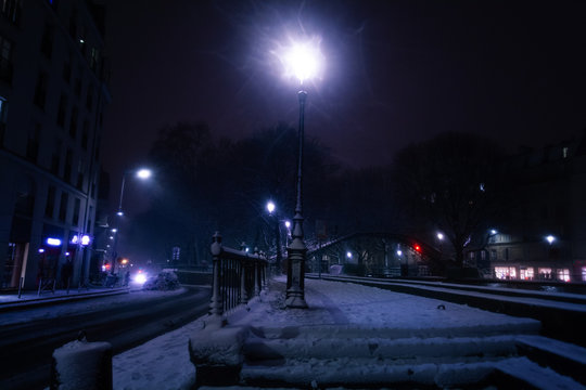 Fototapeta Lamp post illuminating snow-covered street, Paris