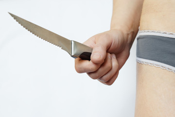 Female hand holds steel sharp knife on white background. The problem of domestic violence