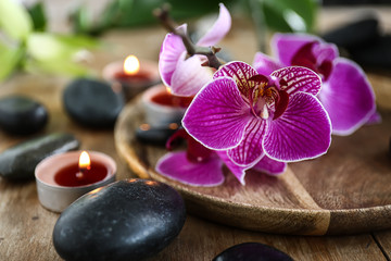 Beautiful spa composition with stones, candles and flowers on table, closeup