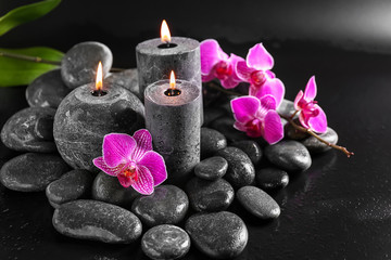 Obraz na płótnie Canvas Candles, flowers and spa stones on dark background