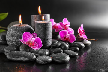 Fototapeta na wymiar Candles, flowers and spa stones on dark background