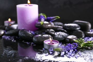 Candles, spa stones and flowers on dark background