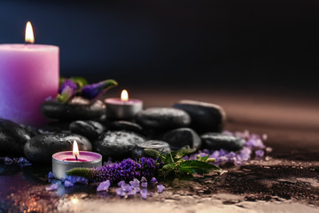 Candles, spa stones and flowers on dark background