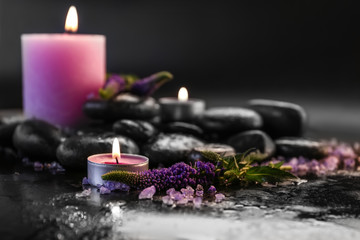 Candles, spa stones and flowers on dark background