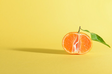 Half of tasty juicy tangerine on color background
