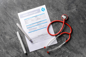 Medical insurance form with stethoscope on grey table. Health care concept