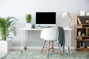 Stylish workplace with modern computer near light wall