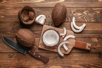 Composition with ripe coconuts and cutting board on wooden background