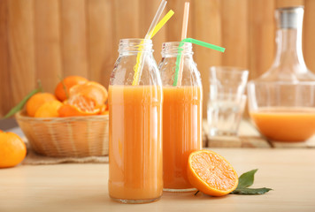 Glass bottles of tangerine juice on table