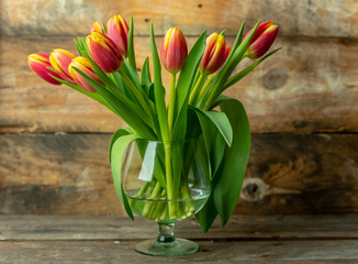 spring yellow-orange tulips on a raw, rustic, wooden background