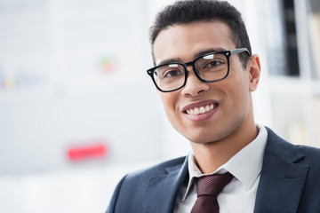 Fototapeta premium portrait of handsome young businessman in eyeglasses smiling at camera