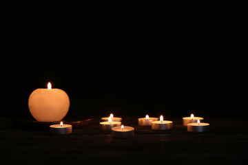 Beautiful burning candles on wooden in darkness